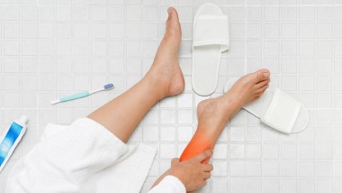 Woman holding her foot after slipping on bathroom floor