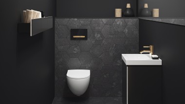 kombinace zlatých prvků na tlačítku s tmavými odstíny koupelny