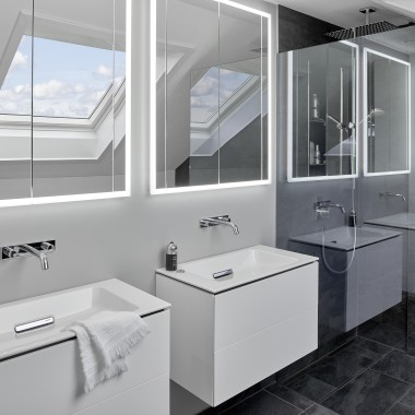 Badkamer onder het dak met twee wastafels en spiegels